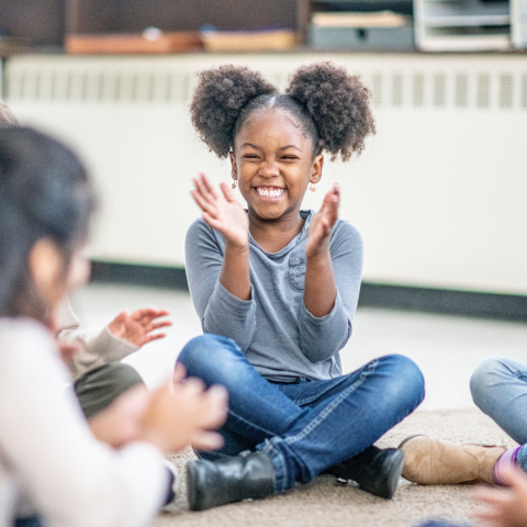 Child clapping their hands while sitting down