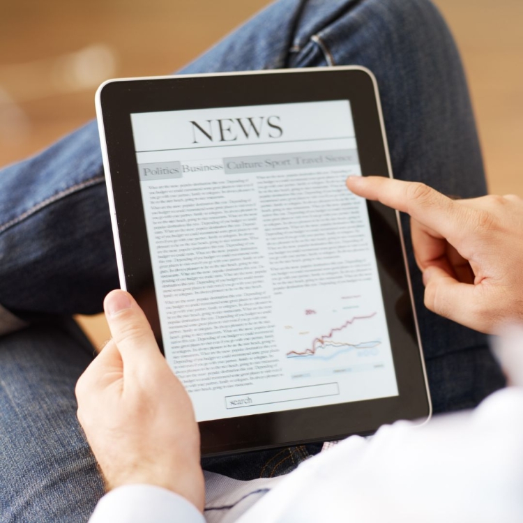 Someone reading a newspaper on a tablet.